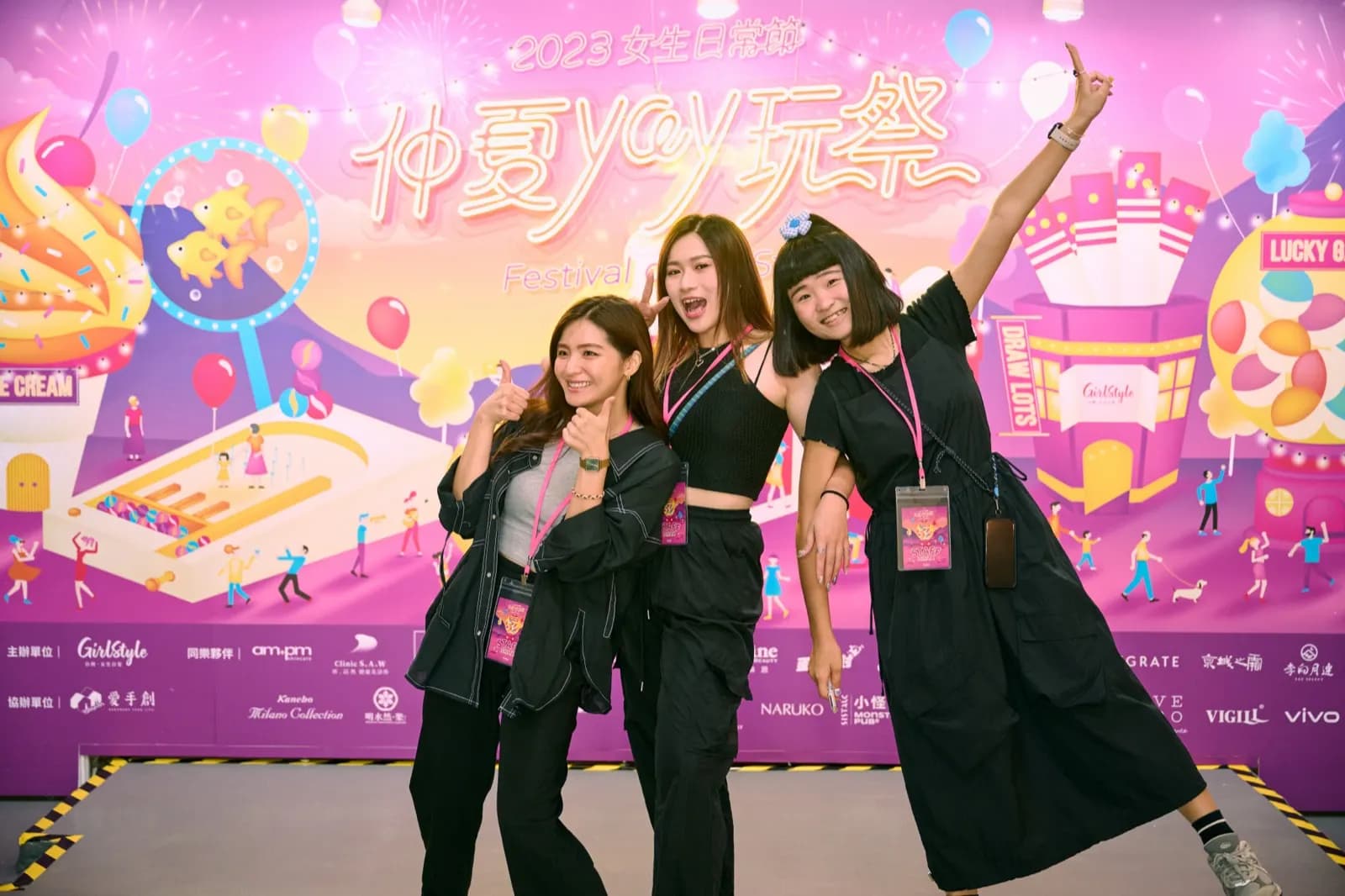 2023 女生日常節主視覺牆前，三位女生比手勢合照；牆面下緣是一整排合作品牌的 logo